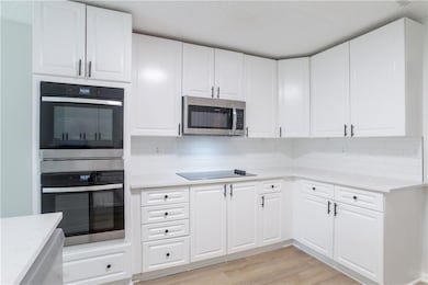 Kitchen with stainless steel appliances, light countertops, tasteful backsplash, light wood-style flooring, and a textured ceiling
