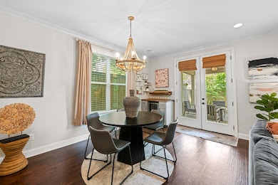 Dining room with crown molding, a chandelier, dark wood finished floors, baseboards, and french doors