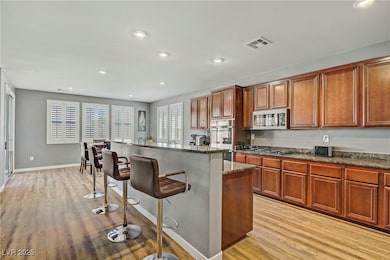Kitchen featuring light wood finished floors, a breakfast bar area, recessed lighting, a kitchen island with sink, and stainless steel appliances