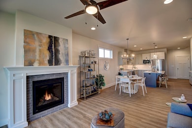 Living room featuring ceiling fan, a fireplace, and light hardwood / wood-style floors