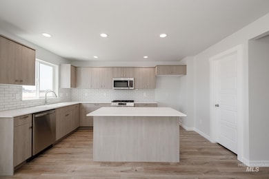 Kitchen featuring tasteful backsplash, light brown cabinets, a kitchen island, appliances with stainless steel finishes, and recessed lighting
