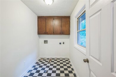 Laundry area with cabinet space, washer hookup, baseboards, tile patterned floors, and a textured ceiling
