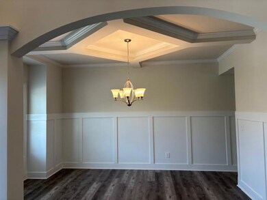 Unfurnished dining area with a decorative wall, coffered ceiling, arched walkways, ornamental molding, and a chandelier