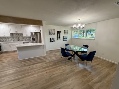 Dining area featuring light wood-type flooring, a chandelier, and a textured ceiling