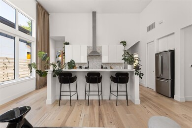 Kitchen featuring a towering ceiling, modern cabinets, freestanding refrigerator, light countertops, and white cabinets