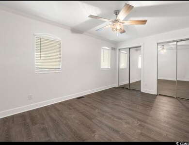 Unfurnished bedroom with two closets, baseboards, dark wood-style floors, and ceiling fan