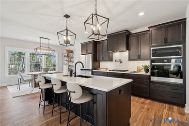 Kitchen with appliances with stainless steel finishes, backsplash, light wood finished floors, dark brown cabinets, and recessed lighting