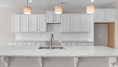 Kitchen featuring white cabinets, decorative backsplash, and light stone counters