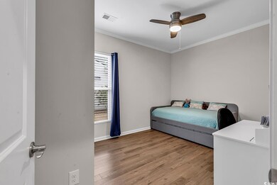 Bedroom with a ceiling fan, visible vents, baseboards, ornamental molding, and light wood-type flooring