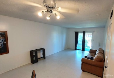 Sitting room with light flooring, a textured ceiling, and ceiling fan