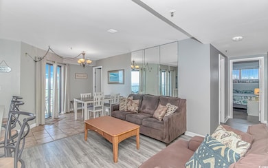 Living room featuring a chandelier, healthy amount of natural light, light wood-type flooring, and baseboards