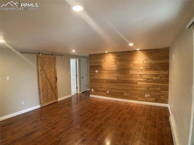 Living room with recessed lighting, baseboards, dark wood-type flooring, and a barn door