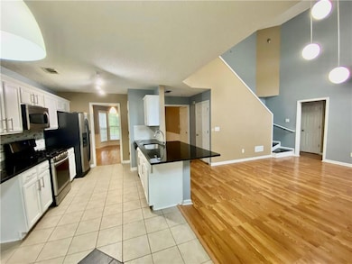 Kitchen featuring stainless steel appliances, white cabinetry, tasteful backsplash, a peninsula, and light tile patterned flooring