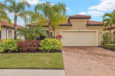 Front of the home with a 2 car attached garage and lush, mature landscaping