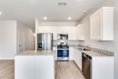 Kitchen featuring a sink, visible vents, light wo
