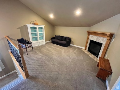 Living area featuring lofted ceiling, carpet flooring, and a tiled fireplace