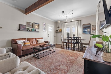 Living room with ornamental molding, wood finished floors, and beam ceiling