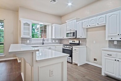 Kitchen featuring backsplash, white cabinets, hard