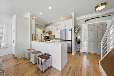 Kitchen featuring appliances with stainless steel finishes, ornamental molding, a sink, tasteful backsplash, and light wood-style flooring