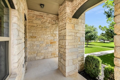 View of exterior entry with stone siding, a porch