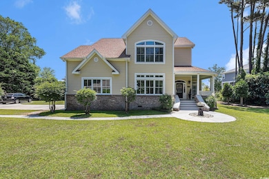 View of front facade featuring covered porch, a front lawn, a shingled roof, and brick siding