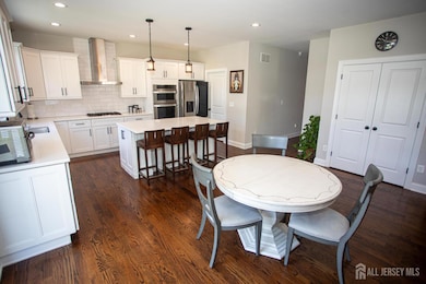 This inviting eat-in kitchen flows seamlessly into the dining space, featuring recessed lighting and rich, dark wood-style floors. The oversized island, double oven, and stainless steel appliances make it a standout space for everyday living and entertaining.