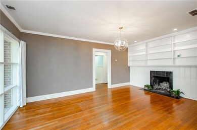 Unfurnished living room with built in shelves, light wood-type flooring, a tiled fireplace, crown molding, and a chandelier