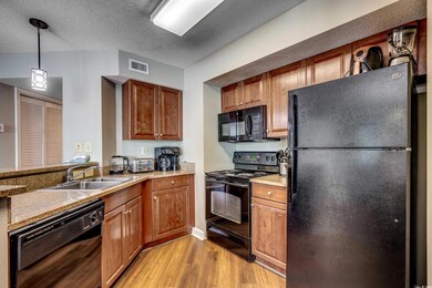 Kitchen with black appliances, a sink, light wood-