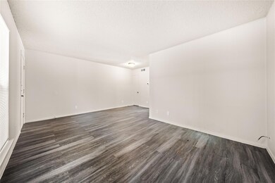 Empty room with a textured ceiling and dark wood-