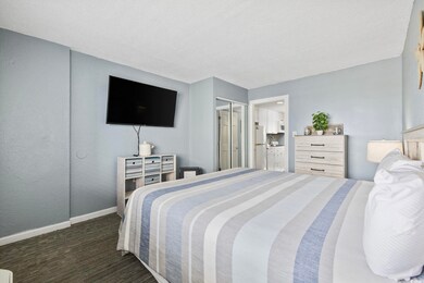 Carpeted bedroom with freestanding refrigerator, baseboards, and connected bathroom