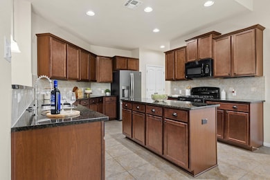 Kitchen featuring decorative backsplash, a center island, black appliances, hanging light fixtures, and recessed lighting