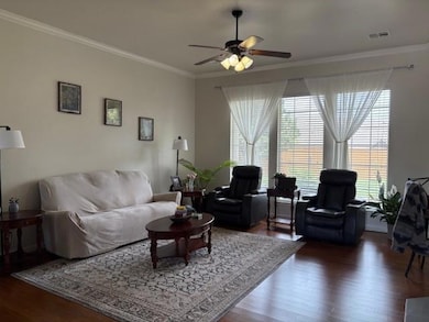 Living room featuring crown molding, a ceiling fan