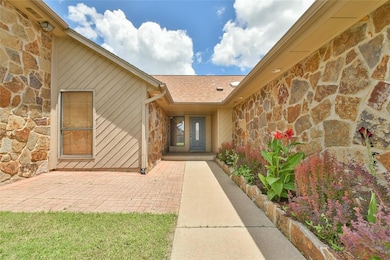 Entrance to property with stone siding, a patio area, and roof with shingles