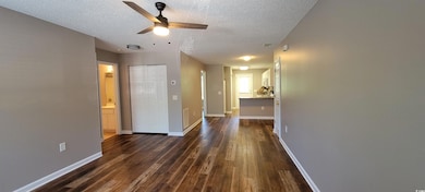 Hall with dark wood finished floors, a textured ceiling, and baseboards