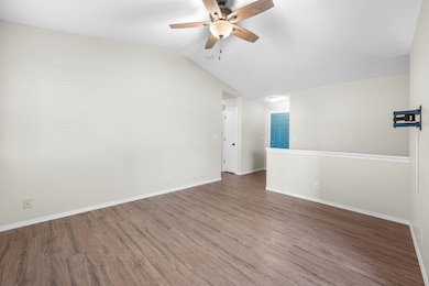 Empty room with vaulted ceiling, wood finished floors, and a ceiling fan
