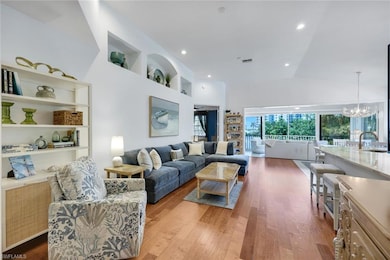 Living room with a chandelier, dark wood-style flooring, high vaulted ceiling, built in features, and recessed lighting