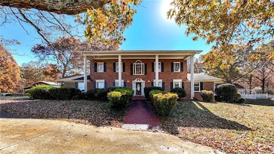 View of front of house with covered porch, brick siding, and a front lawn