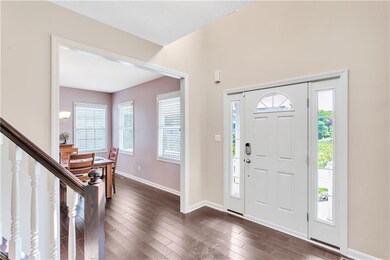 Generous entry way with hardwood floors and custom railing to the upper level.
