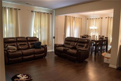 Living area with a chandelier, dark wood-style floors, and plenty of natural light