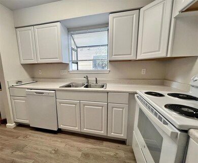 Kitchen featuring white appliances, white cabinets, light countertops, and light wood-style flooring
