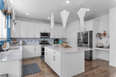 Kitchen featuring tasteful backsplash, white cabinets, stainless steel appliances, dark wood finished floors, and a textured ceiling