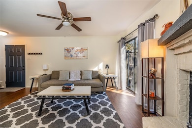 Living room featuring ceiling fan and dark hardwoo
