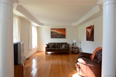 Living room has a tray ceiling with crown molding