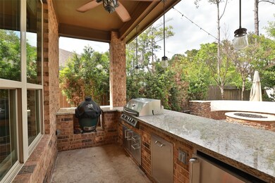 outdoor kitchen with green egg, gas grill, pull out trash and fridge with a huge bar area to entertain.