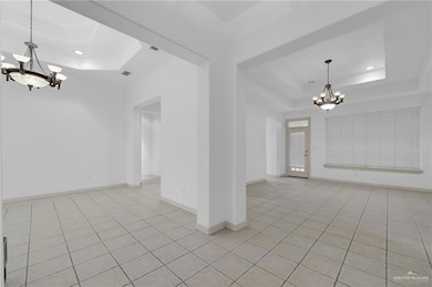 Empty room featuring light tile patterned flooring, a tray ceiling, a chandelier, and recessed lighting
