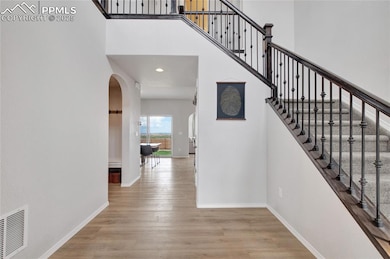 Staircase featuring arched walkways, a towering ceiling, wood finished floors, and recessed lighting