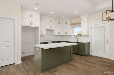 Kitchen featuring green cabinetry, white cabinetry, wood finish floors, recessed lighting, and tasteful backsplash