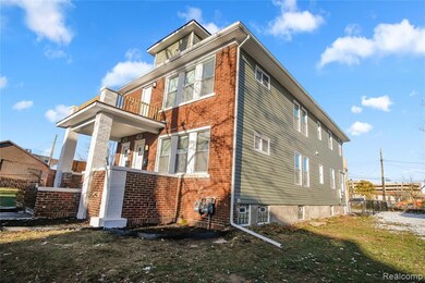 View of side of property with brick siding, a balcony, and a yard