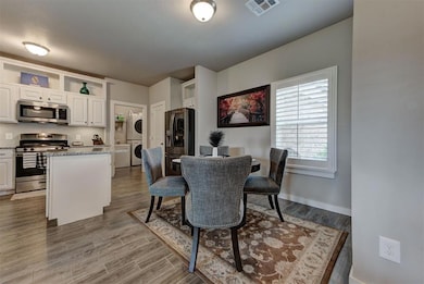 Dining space with estacked washer and dryer, wood finished floors, and baseboards