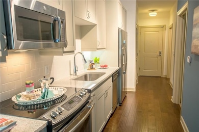 Kitchen featuring appliances with stainless steel finishes, tasteful backsplash, white cabinets, sink, and dark hardwood / wood-style flooring